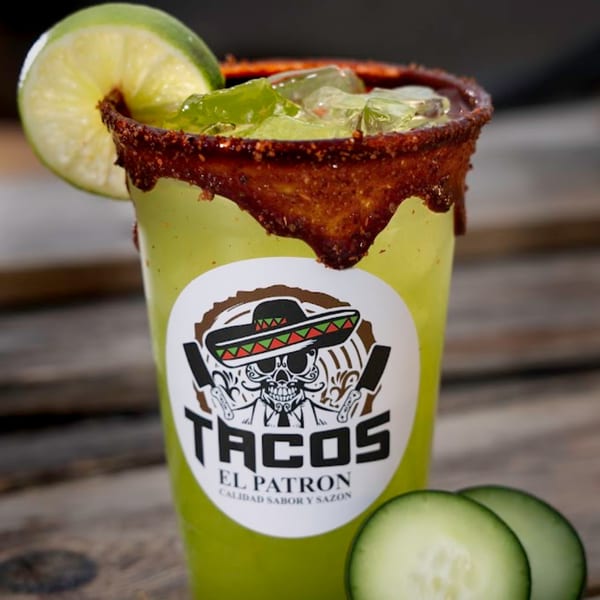 A Tacos El Patron drink with a chili-lime rim, ice, lime, and cucumber slices.