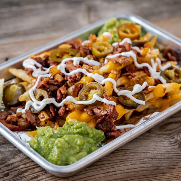 Loaded Tacos El Patron fries with carne asada, cheese, jalapeños, sour cream, and guacamole.